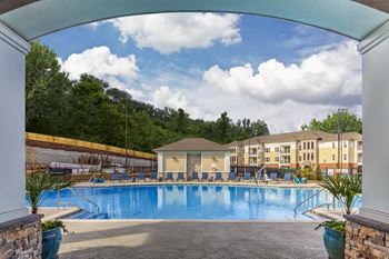 A large swimming pool surrounded by a stone wall and trees